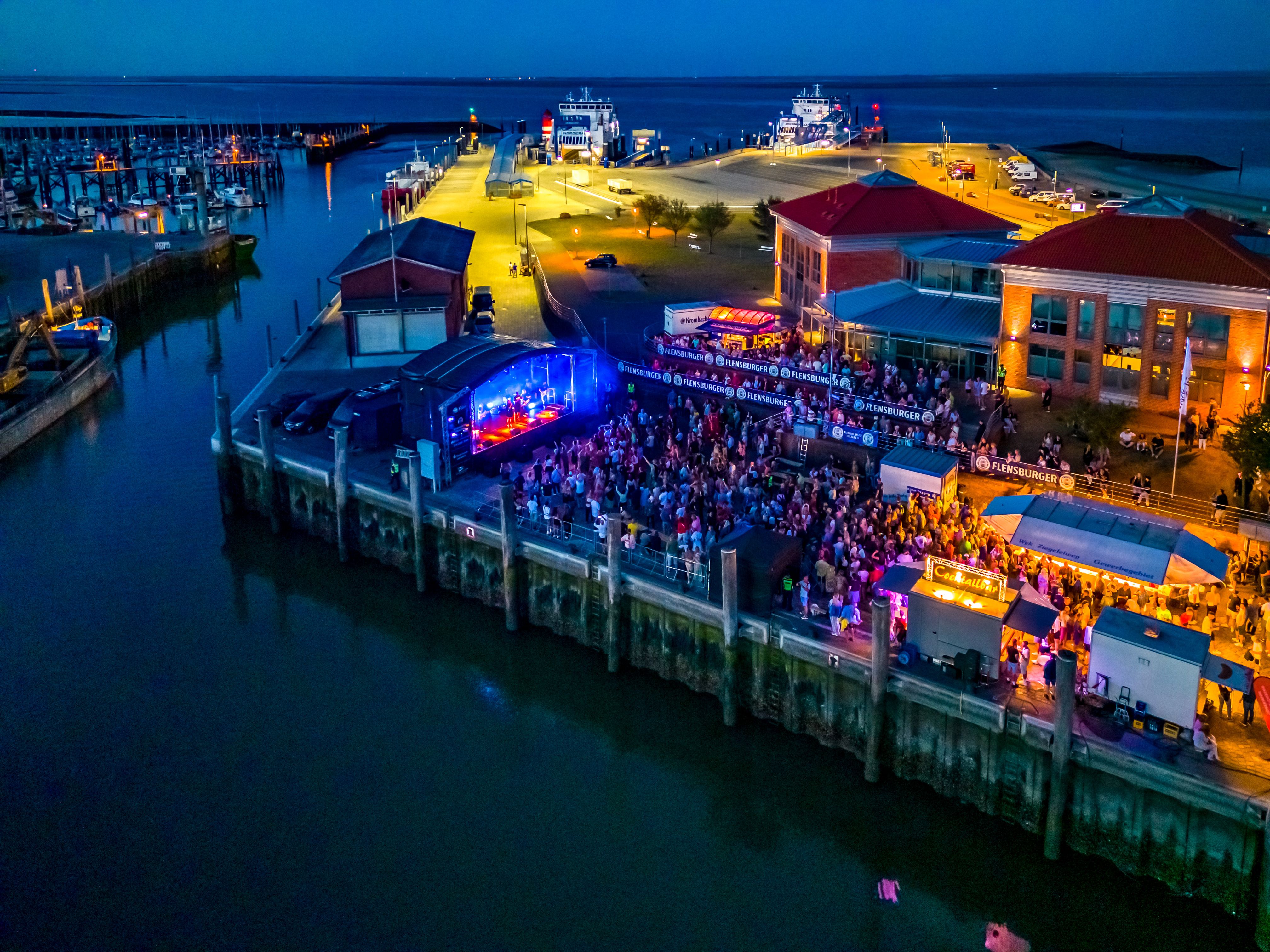Binnenhafen bei Nacht während eines Hafenfestivals mit Lichtern, Menschen und Bühne