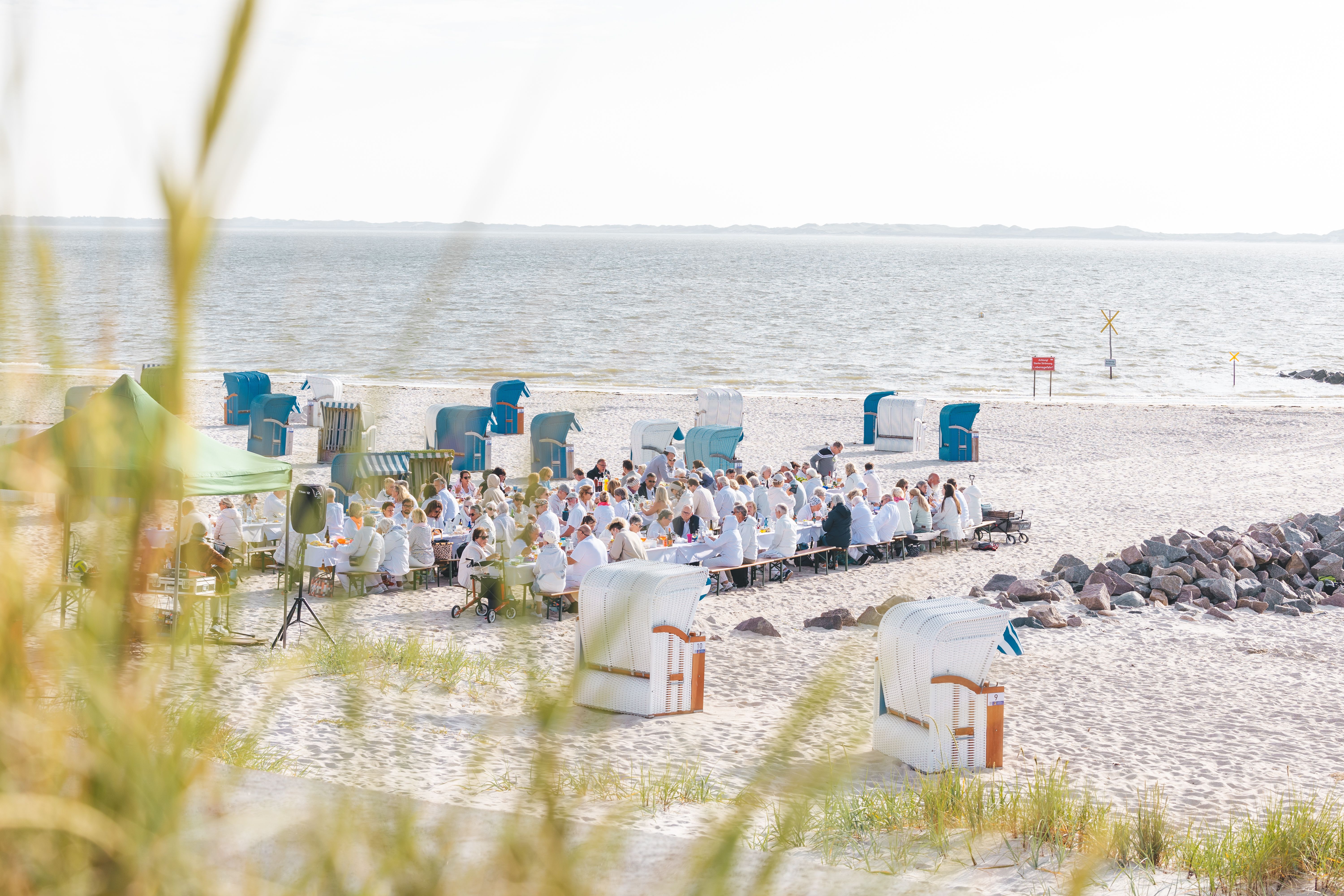 Strandpanorama mit Strandkörben und Personen auf Bänken