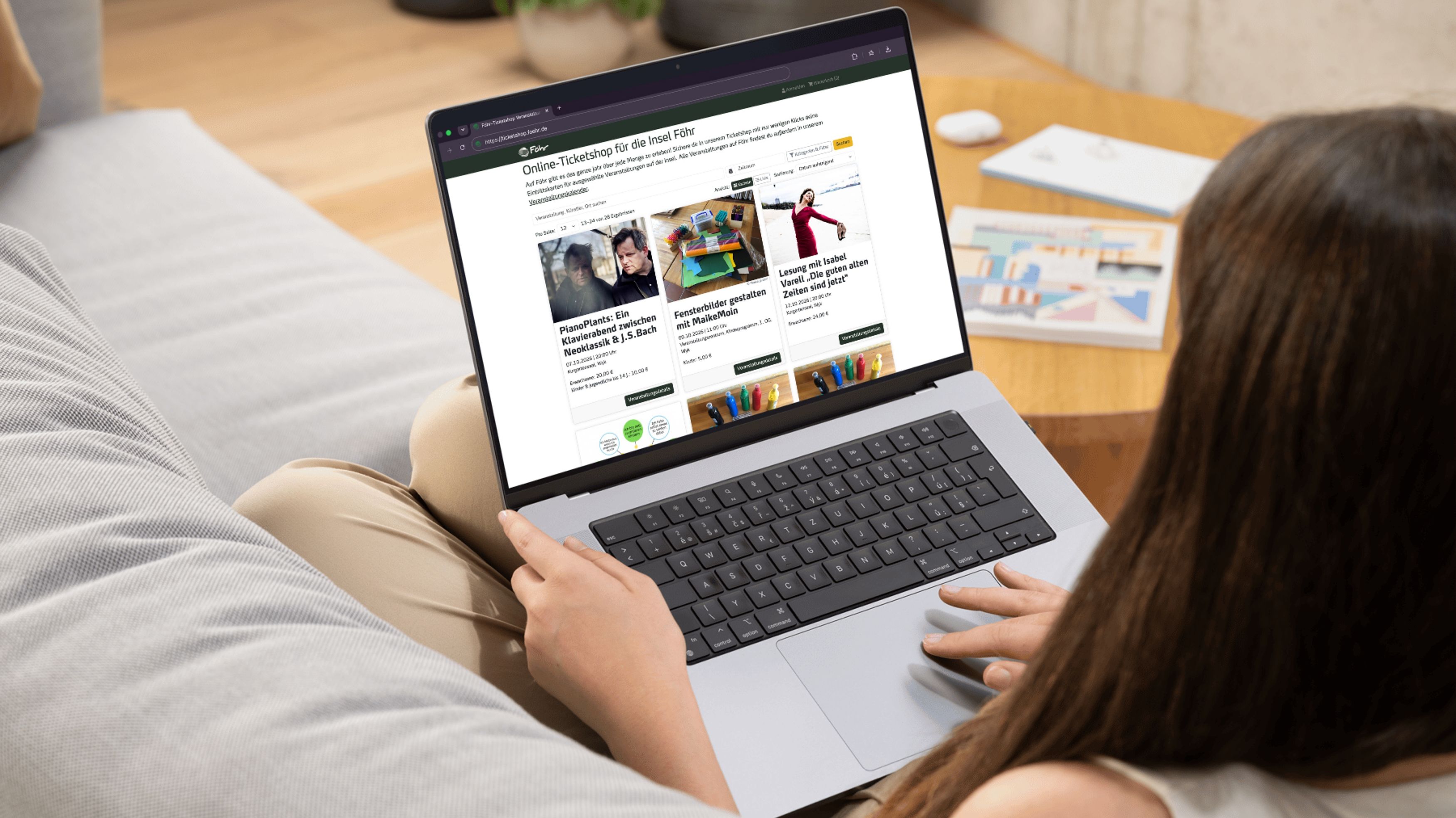 Frau surft auf Laptop im Föhr-Ticketshop von Sofa aus