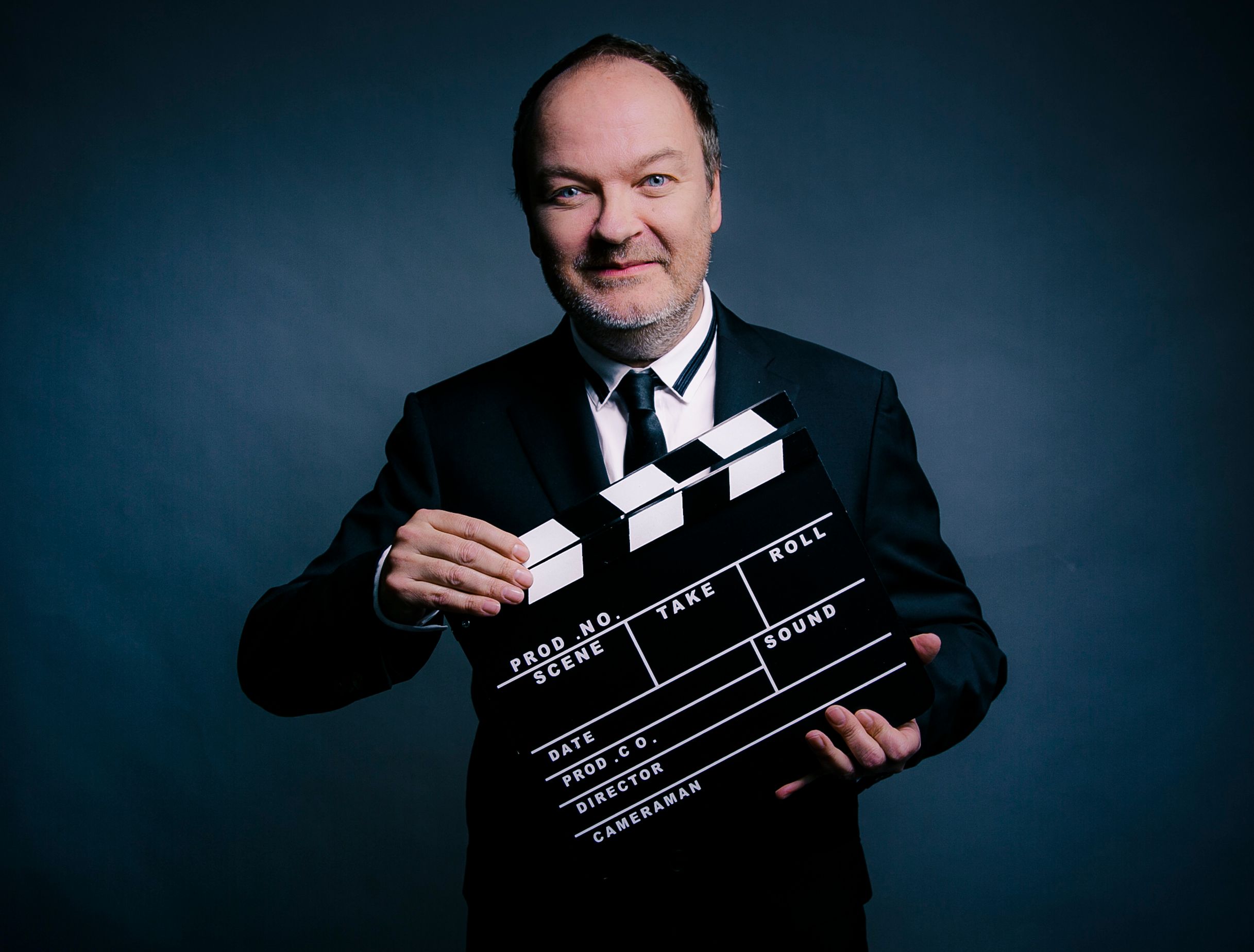 Mann im dunklen Anzug mit einer Filmklappe in der Hand